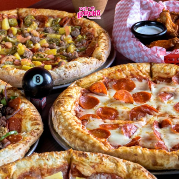 Two pizzas, one pepperoni and one with various toppings, with chicken wings and an 8-ball.