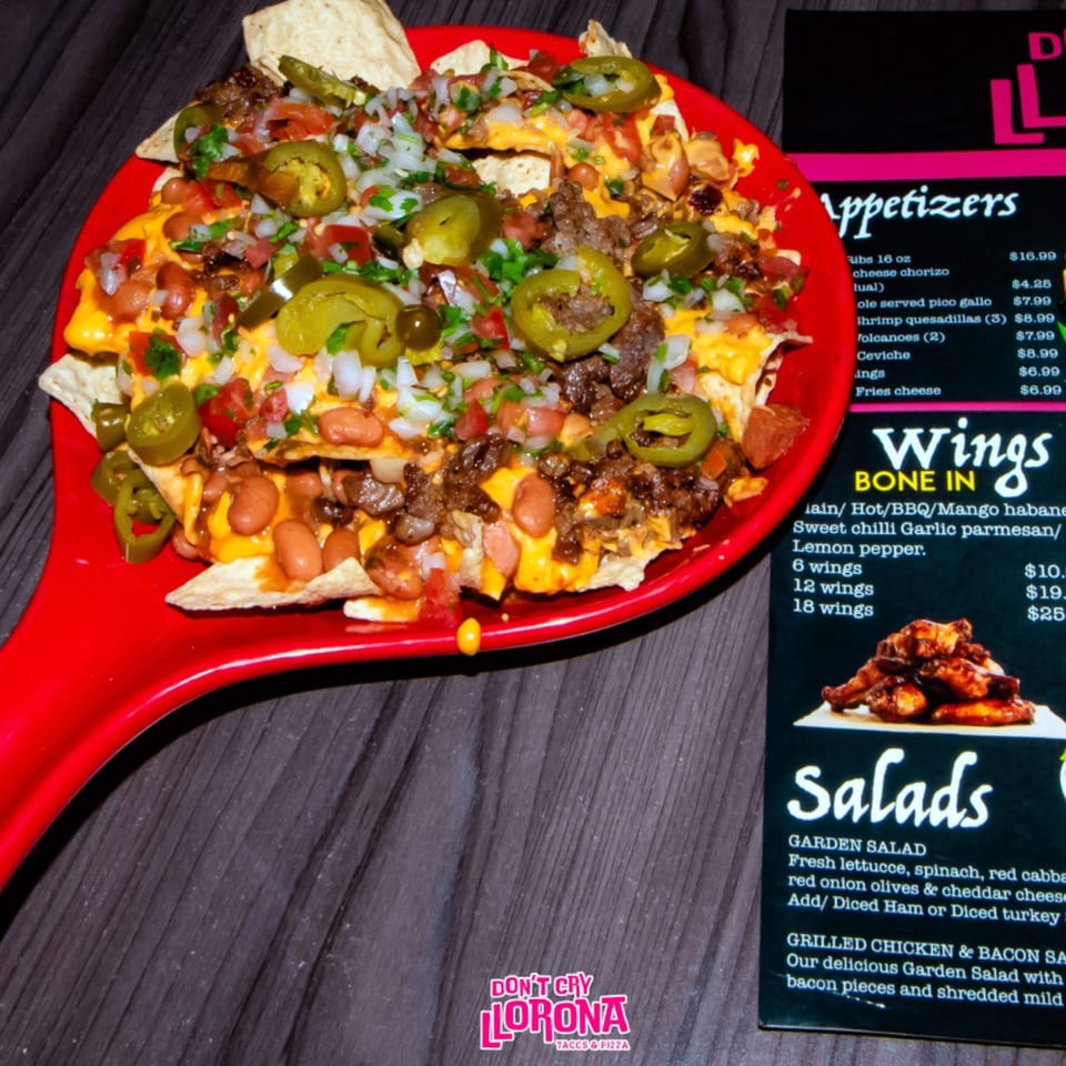 A large platter of Dont Cry Llorona nachos with cheese, beans, meat, jalapeños, and pico de gallo.