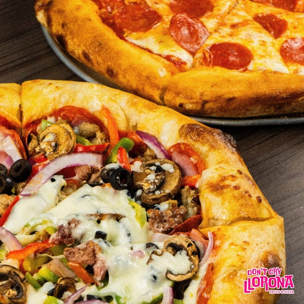 Two pizzas, one pepperoni and one with various toppings, on a dark wooden surface.